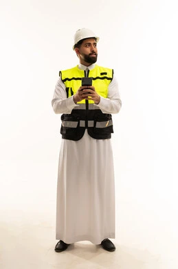 مهندس سعودي يرتدي سترة السلامة ويمسك هاتف