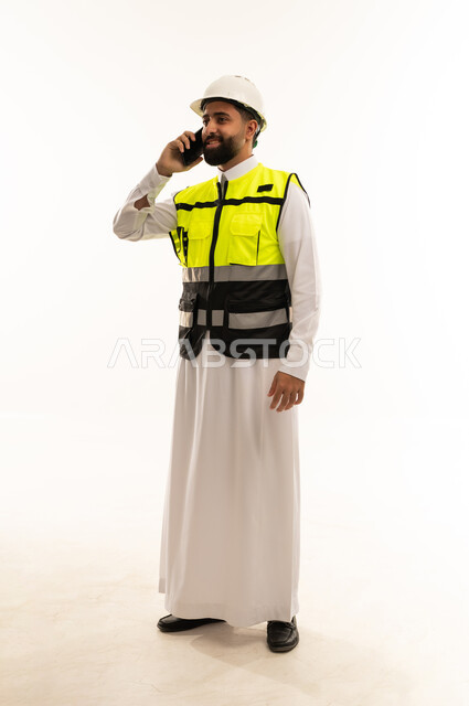 مهندس سعودي يرتدي سترة السلامة ويتحدث بالجوال
