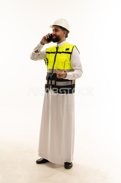 مهندس سعودي يرتدي سترة السلامة يتحدث بالجوال