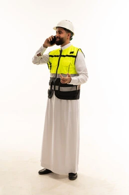 مهندس سعودي يرتدي سترة السلامة يتحدث بالجوال
