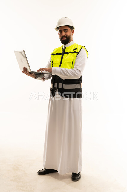مهندس سعودي يحمل كمبيوتر محمول بمعدات السلامة