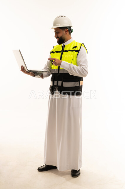 مهندس سعودي يحمل كمبيوتر محمول بملابس السلامة