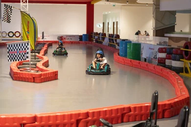 أطفال يقودون سيارات الكارتينج في مضمار سباق داخلي