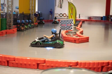 طفلة تقود سيارة سباق في مضمار داخلي