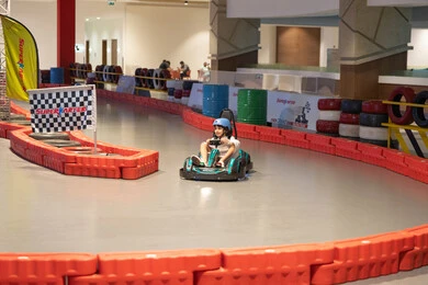 طفل عربي يقود سيارة كارتينج في مسار سباق داخلي