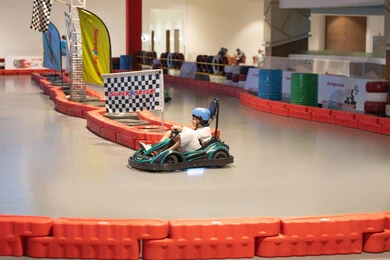 طفل سعودي يقود سيارة كارتينج في مضمار سباق داخلي