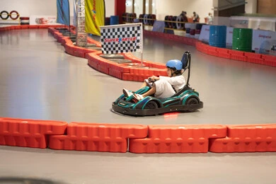 طفل سعودي بالثوب يقود سيارة كارتينج في حلبة داخلية