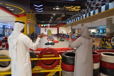 رجل وامرأة إماراتيان في مضمار سباق كارتينج داخلي