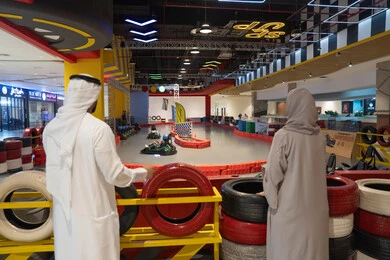 زوجان عربيان يشاهدان سباق كارتينج داخلي في مركز ترفيهي