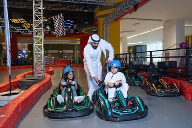 رجل إماراتي مع أطفال في سباق كارتينج داخلي