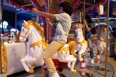 أطفال عرب يركبون لعبة الأحصنة في مدينة ملاهي مغلقة