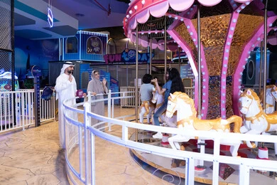 عائلة إماراتية في مدينة ملاهي داخلية عند لعبة الدوامة