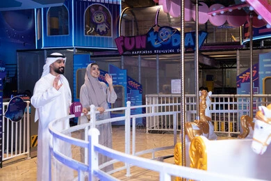 Emirati Couple at Indoor Amusement Park Carousel