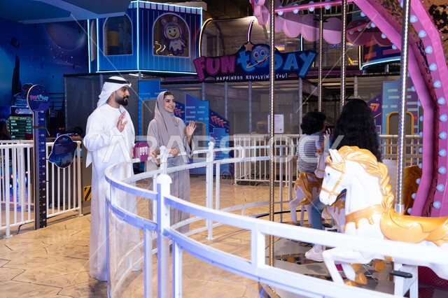 Emirati Couple at Indoor Amusement Park Carousel