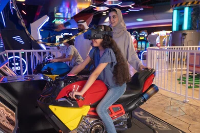 فتاة إماراتية تلعب سباق دراجات افتراضي مع والدتها