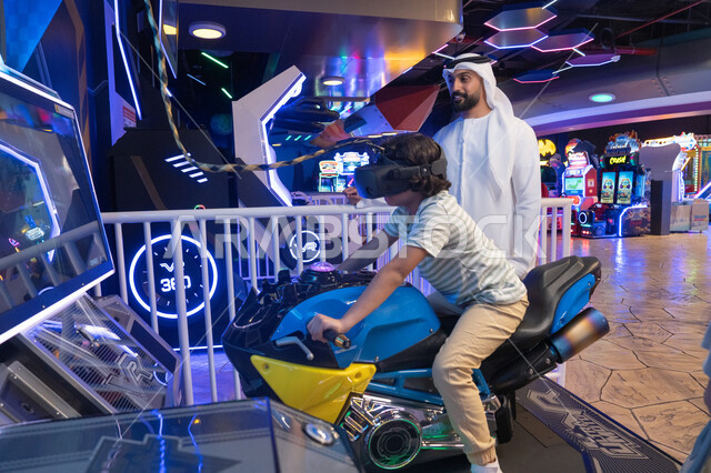 رجل إماراتي وطفل في مركز ألعاب واقع افتراضي