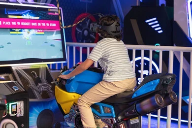 طفل عربي يلعب سباق دراجات نارية بالواقع الافتراضي