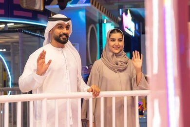 رجل وامرأة من الإمارات يلوحان في مركز ترفيهي