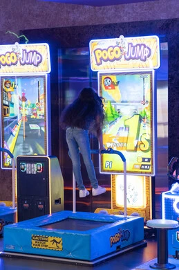 فتاة عربية تلعب لعبة أركيد تفاعلية في مركز ترفيهي