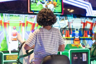 طفل عربي يلعب لعبة سباق الخيول في مركز ترفيهي