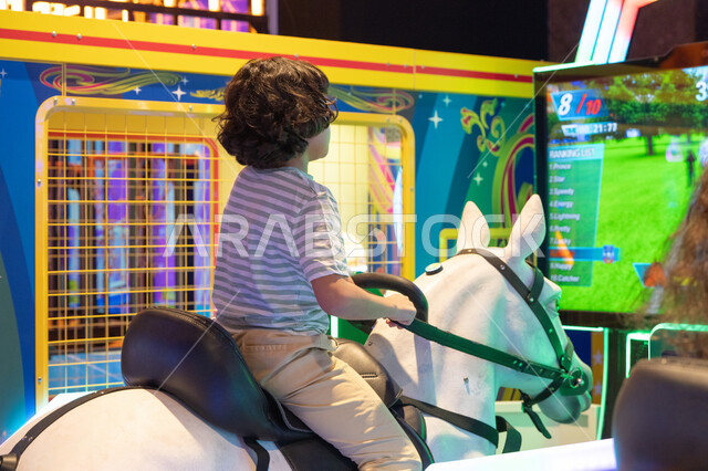 طفل يلعب بجهاز محاكاة ركوب الخيل في صالة ألعاب