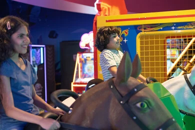 أطفال سعوديون يركبون الخيل في مدينة ملاهي مغلقة