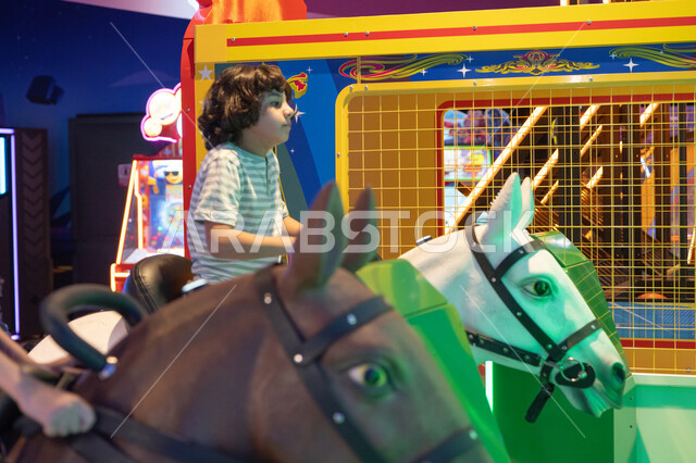 Arab Boy Riding Horse Simulator in Indoor Amusement Park