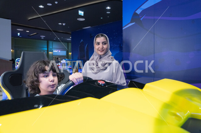 امرأة سعودية وطفل يلعبان محاكي سباق السيارات
