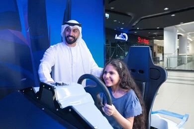 رجل إماراتي وفتاة يستخدمان محاكي سباق السيارات رجل إماراتي وفتاة يستخدمان محاكي سباق السيارات