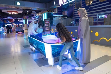 Saudi Family Playing Air Hockey at Indoor Center Saudi Family Playing Air Hockey at Indoor Center