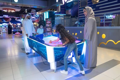 Emirati Family Playing Air Hockey in Indoor Arcade Emirati Family Playing Air Hockey in Indoor Arcade