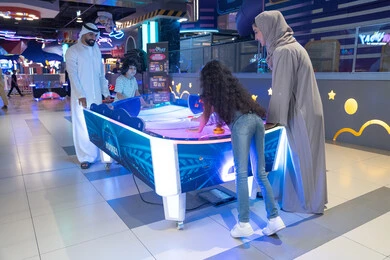 Emirati Family Playing Air Hockey in Modern Arcade