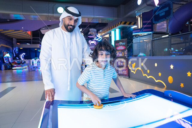 أب وابن إماراتي يلعبان الهوكي الهوائي في صالة ألعاب