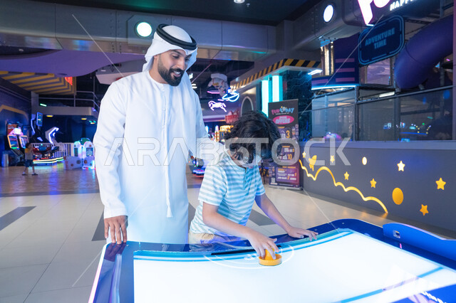 أب إماراتي وابنه يلعبان هوكي الهواء في مدينة الملاهي