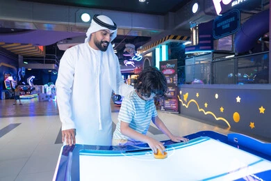أب إماراتي وابنه يلعبان هوكي الهواء في مدينة الملاهي