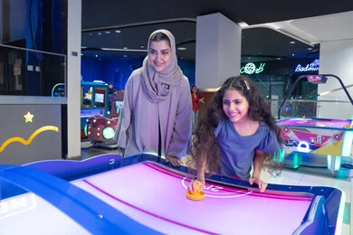 Arab Mother and Daughter Playing Air Hockey Indoor Arab Mother and Daughter Playing Air Hockey Indoor