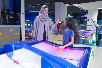 Saudi Mother and Daughter Playing Air Hockey in Arcade