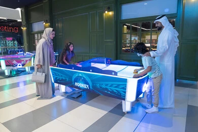 Emirati Family Playing Air Hockey in Entertainment Center Emirati Family Playing Air Hockey in Entertainment Center