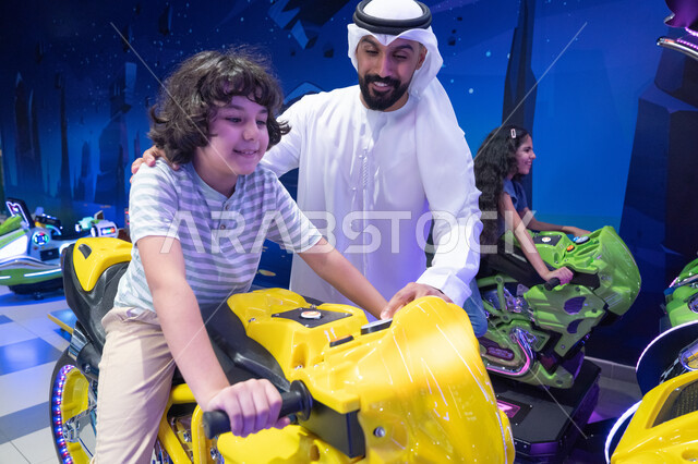 أب إماراتي وابنه يلعبان لعبة دراجات نارية في أركيد