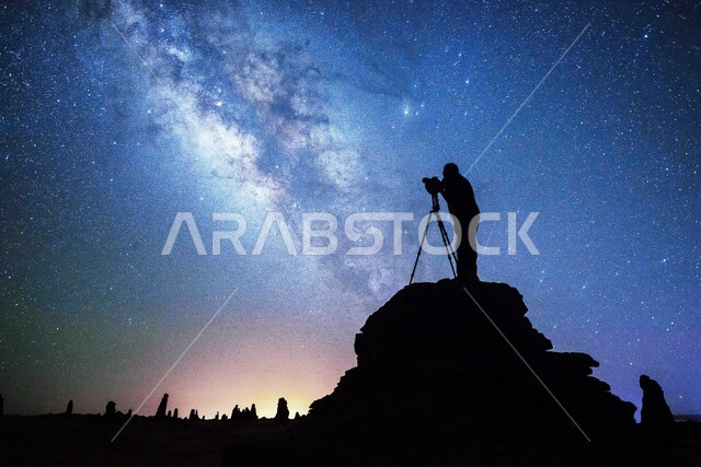 صورة ظلية إبداعية لرجل يقوم بإلتقاط الصور في محافظة العلا مع مجرة درب التبانة في السماء ، المملكة العربية السعودية ، السياحة في السعودية ، معالم أثرية سياحية في السعودية ، جمال الطبيعة الصحراوية في محافظة العلا