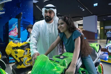 رجل إماراتي وطفلة في مركز ألعاب المحاكاة