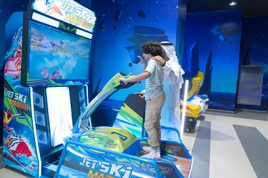 رجل وطفل إماراتي يلعبان داخل صالة ألعاب إلكترونية حديثة