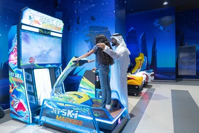 رجل إماراتي وطفلة يلعبان في مركز ألعاب ترفيهي