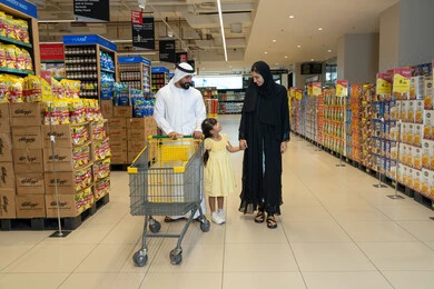 عائلة إماراتية تتسوق مع عربة في ممر السوبر ماركت