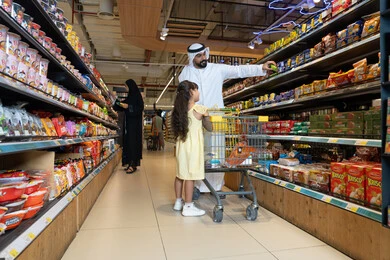 رجل إماراتي يتسوق في ممر السوبر ماركت مع ابنته