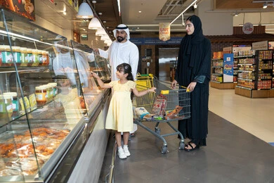 عائلة إماراتية تتسوق في قسم المأكولات بالسوبر ماركت