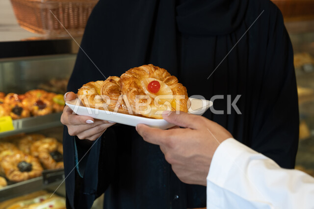 رجل إماراتي يشتري معجنات الفواكه في المخبز لقطة قريبة