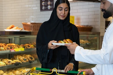 Emirati Couple Buying Pastries in Bakery Store