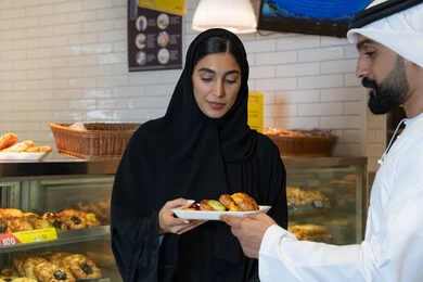 Emirati Couple Buying Pastries in a Traditional Bakery Emirati Couple Buying Pastries in a Traditional Bakery