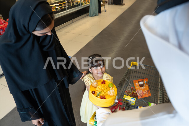 عائلة إماراتية تتسوق في السوبر ماركت مع كعكة فواكه